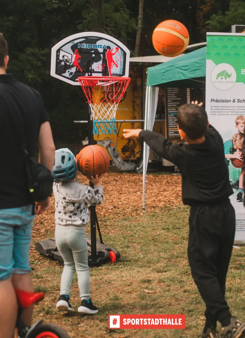 Zwei Jungen werfen mit Basketb&auml;llen auf einen kleinen Basketballkorb