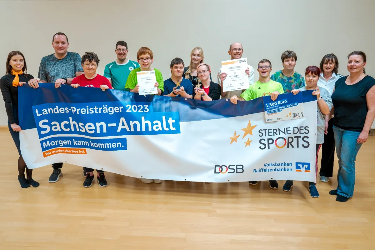 Sportlerinnen und Sportler des Tanztreffs halten ein Banner der Volksbank Halle bei der Siegerehrung der Sterne des Sports.