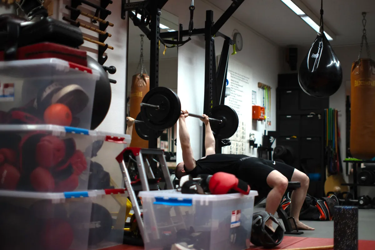 Eine Person übt Bankdrücken im Fitnessbereich.