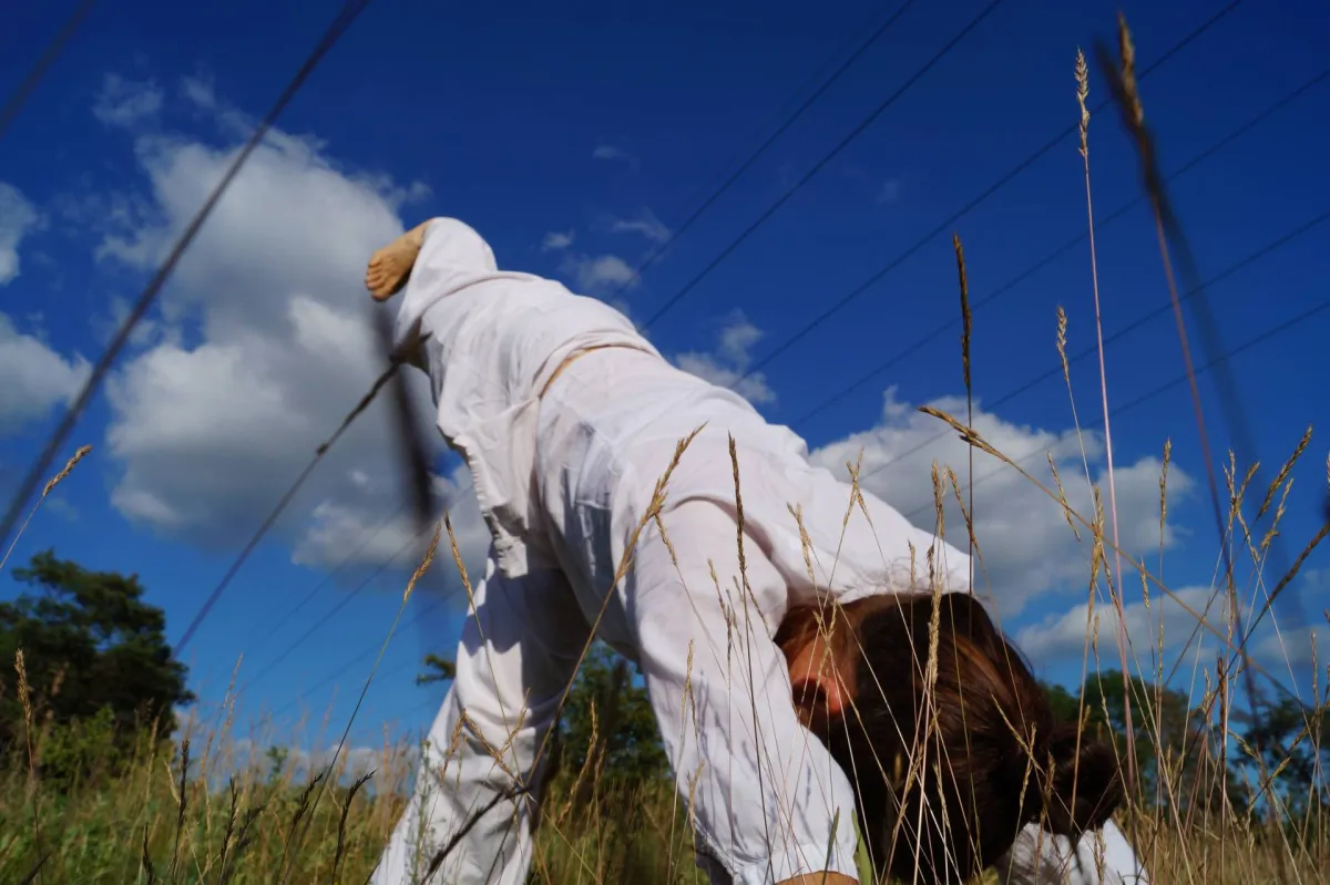eine Person macht Yoga auf einer grünen Wiese