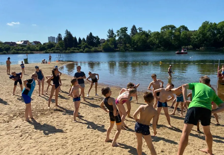 Am Ufer eines Flusses machen junge Menschen Aufwärmübungen.