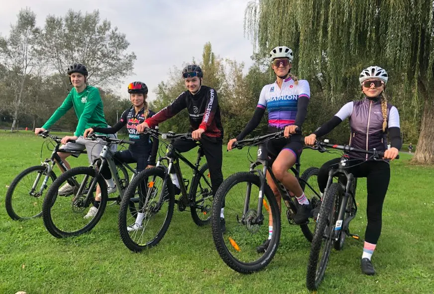 Fünf junge Sportlerinnen und Sportler posieren mit Rennrädern. 