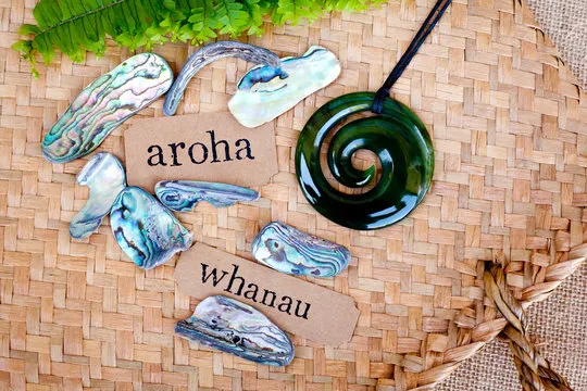 Steine, Spiralen und Kärtchen mit den Worten "aroha" und "whanau" auf Bambusmatten.