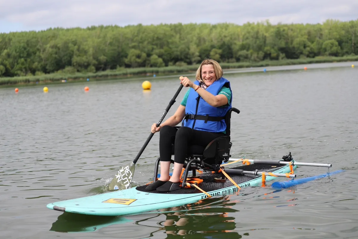 Para-SUP Eine Frau im Rollstuhl paddelt auf einem SUP auf einem See.