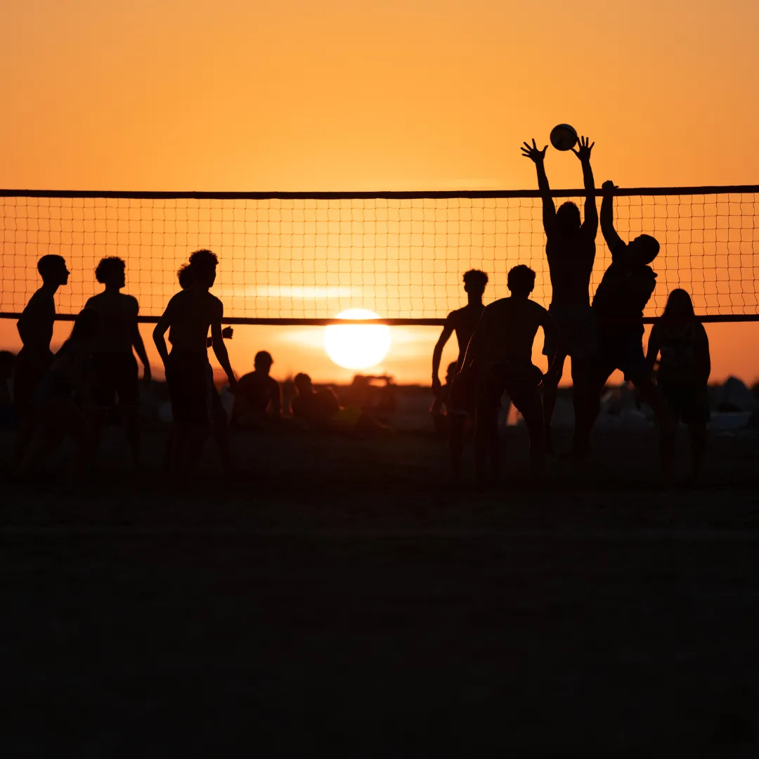 Symbolbild Vereinswochenende Menschen spielen Volleyball im Sonnenuntergang.