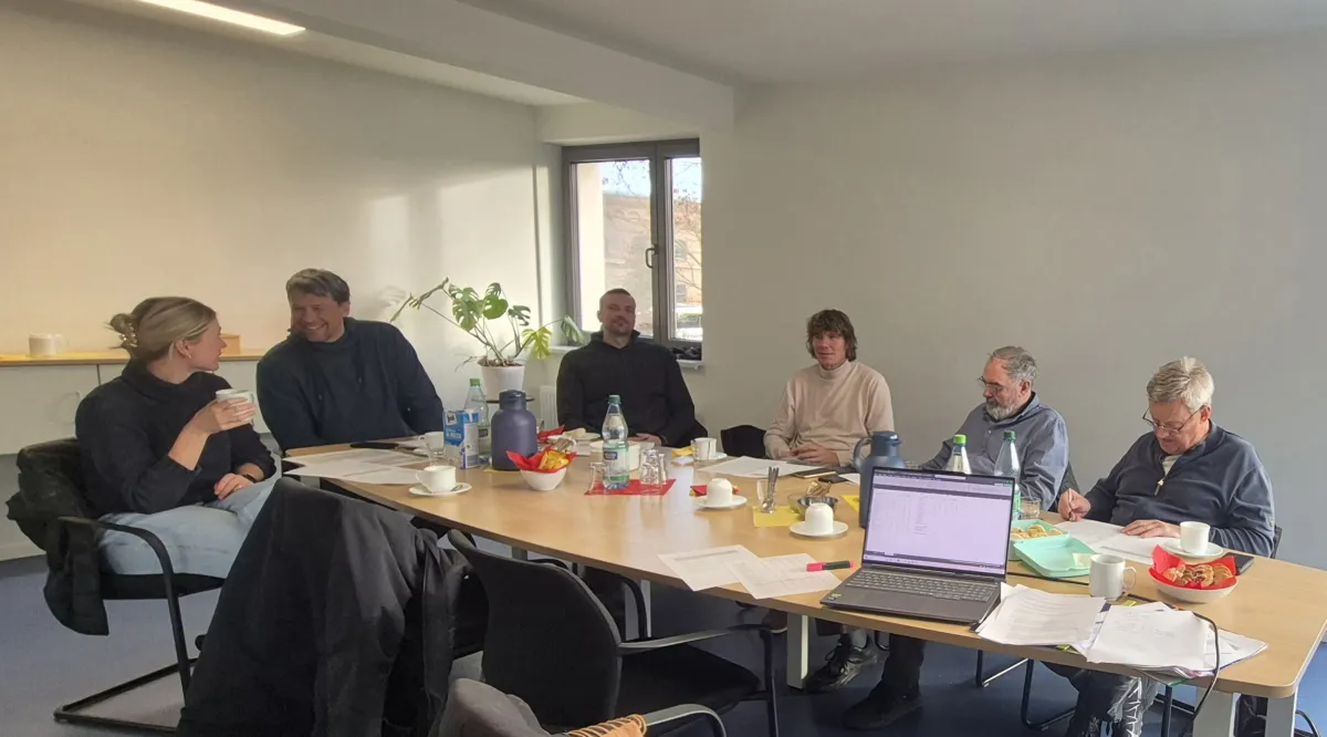 Mehrere Personen sitzen an einem Tisch und beraten sich.