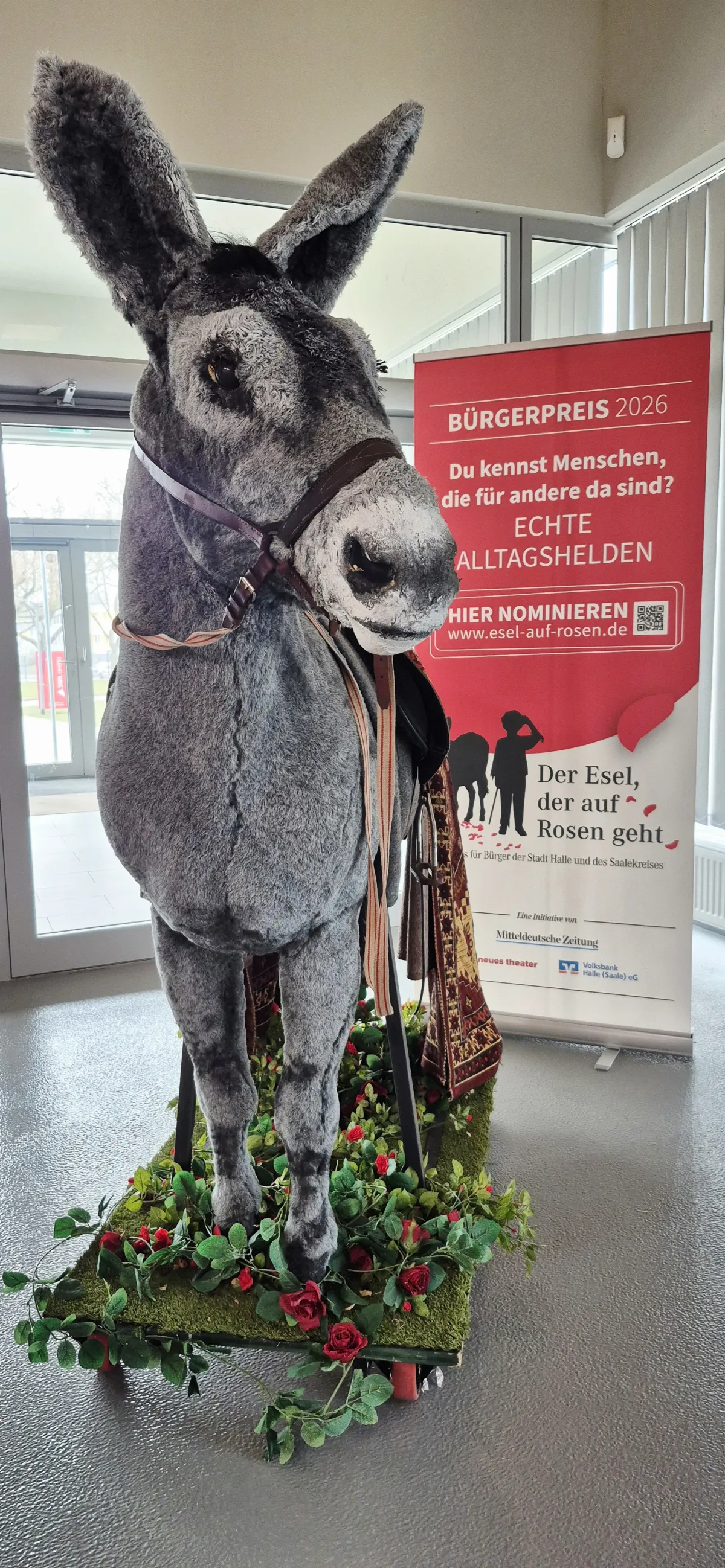 Eselfigur vor einem informativen Roll-Up zum B&uuml;rgerpreis "Der Esel, der auf Rosen geht" in der SWH.arena. 
