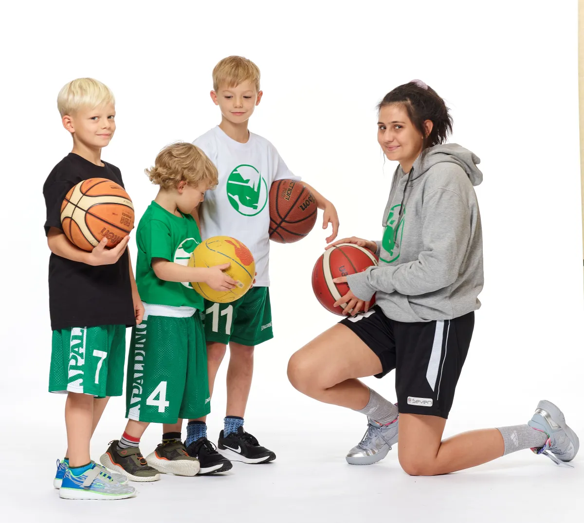Junge Basketballtrainerin mit drei Jungen.