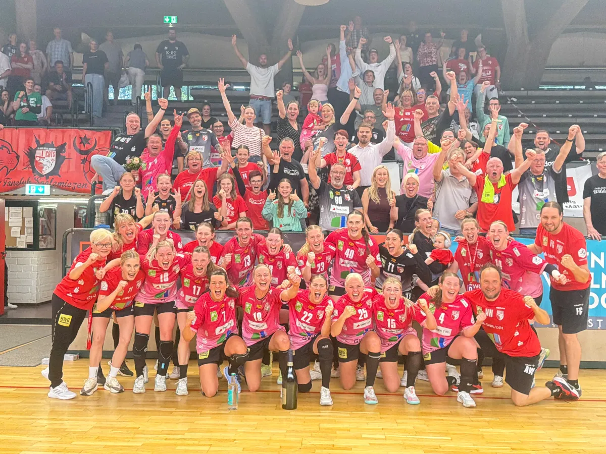 Frauen in roten Trikots stehen aufgereiht und jubeln f&uuml;r ein Foto.