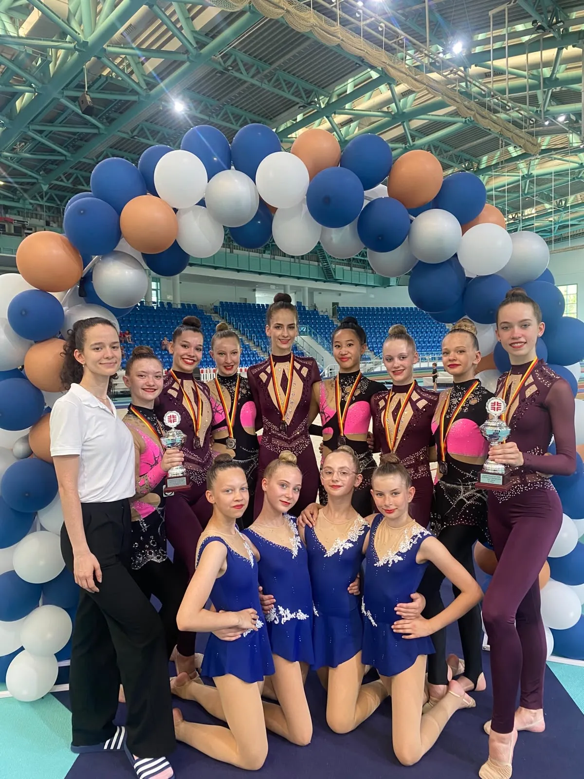 Gro&szlig;e Gruppe junger Frauen in Gymnastikanz&uuml;gen posierend vor Torbogen aus Ballons