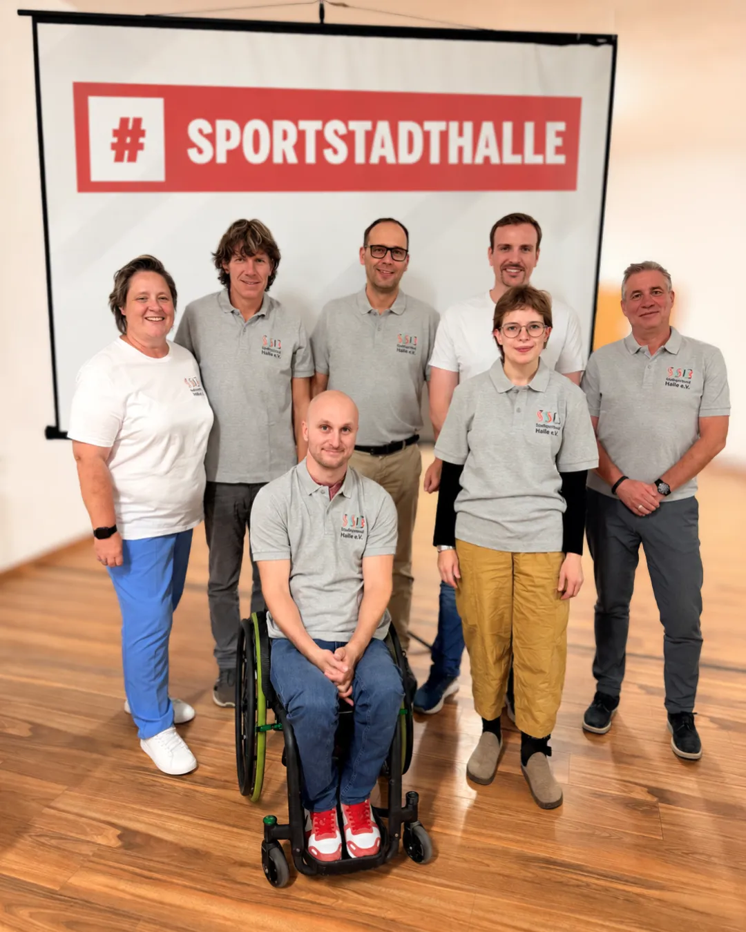 7 Personen in einheitlichen Shirts mit SSB-Logo vor Leinwand
