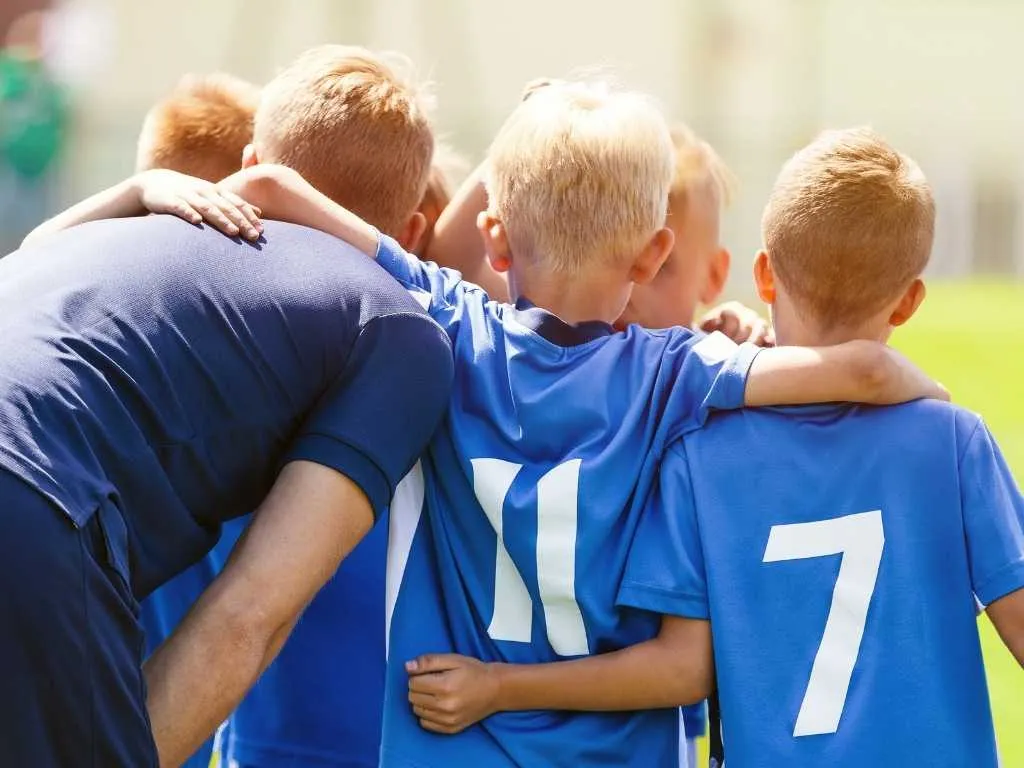 Teamkreis von Jungen und Trainer in blauen Trikots