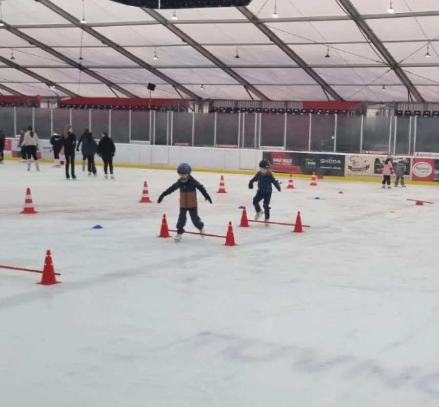 Kinder mit Schlittschuhen auf dem Eis, die einen Hindernisparcours absolvieren