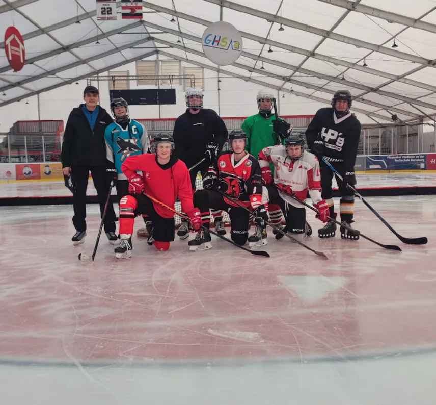 Eine Gruppe von Eishockey-Spielern mit Schlägern und Trainingskleidung auf dem Eis