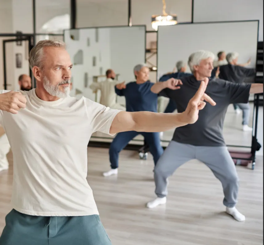 Mehrere Männer in sportlicher Qi Gong-Haltung in einem Sportraum.