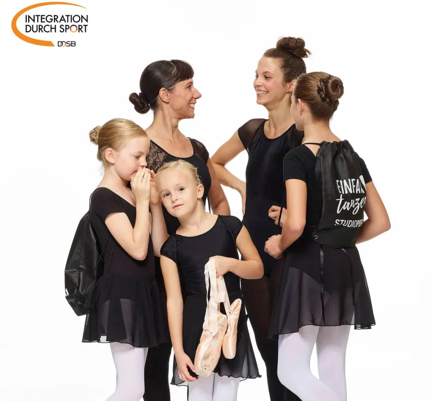 Ballerinas verschiedenen Alters in schwarz-weißer Kleidung stehen im Kreis.