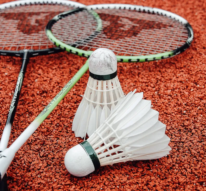 Zwei Badmintonschläger und zwei Federbälle auf dem Boden.