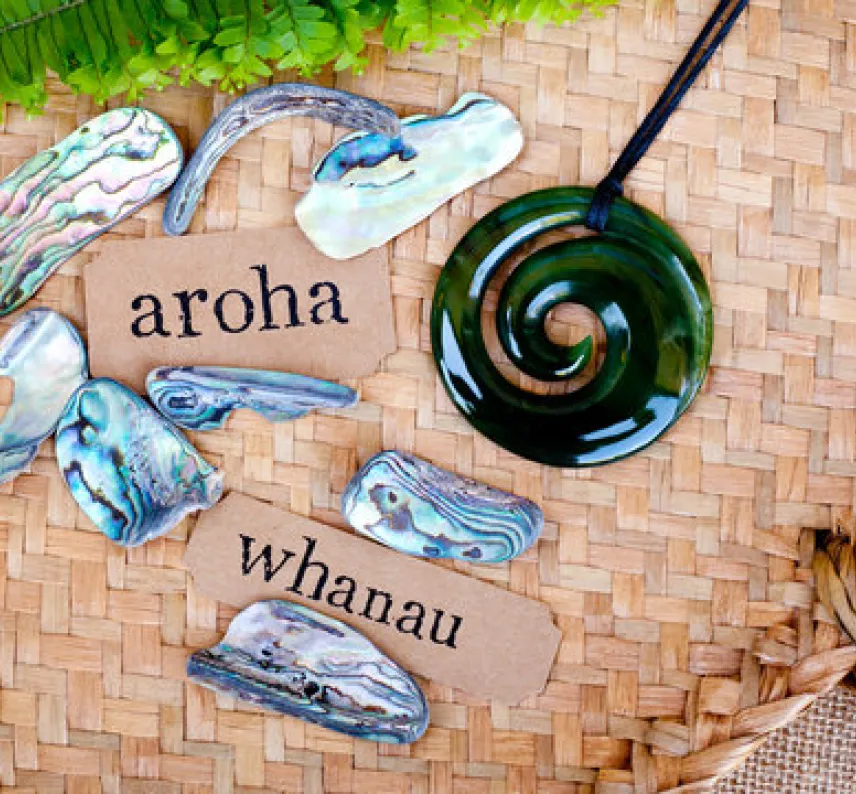 Steine, Spiralen und Kärtchen mit den Worten "aroha" und "whanau" auf Bambusmatten.
