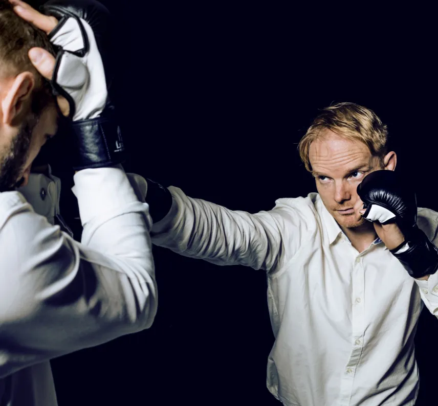 zwei formal gekleidete Personen kämpfen mit MMA-Handschuhen