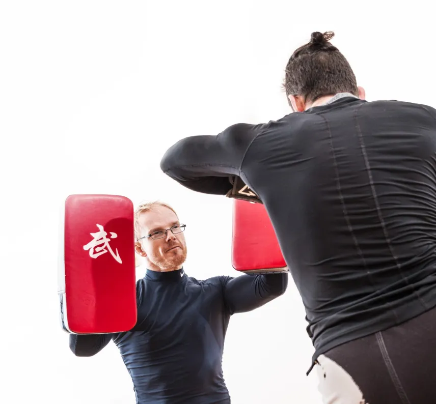 Zwei Trainingspartner trainieren Ellenobgenschl&auml;ge auf Pratzen