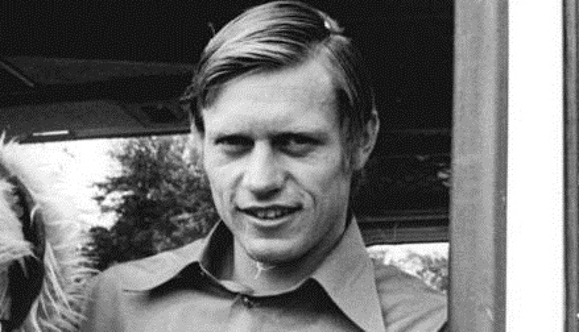 Zu sehen ist ein Schwarz-Weiß-Foto von Bernd Bransch im Hemd mit einem Maskottchen in der Hand.