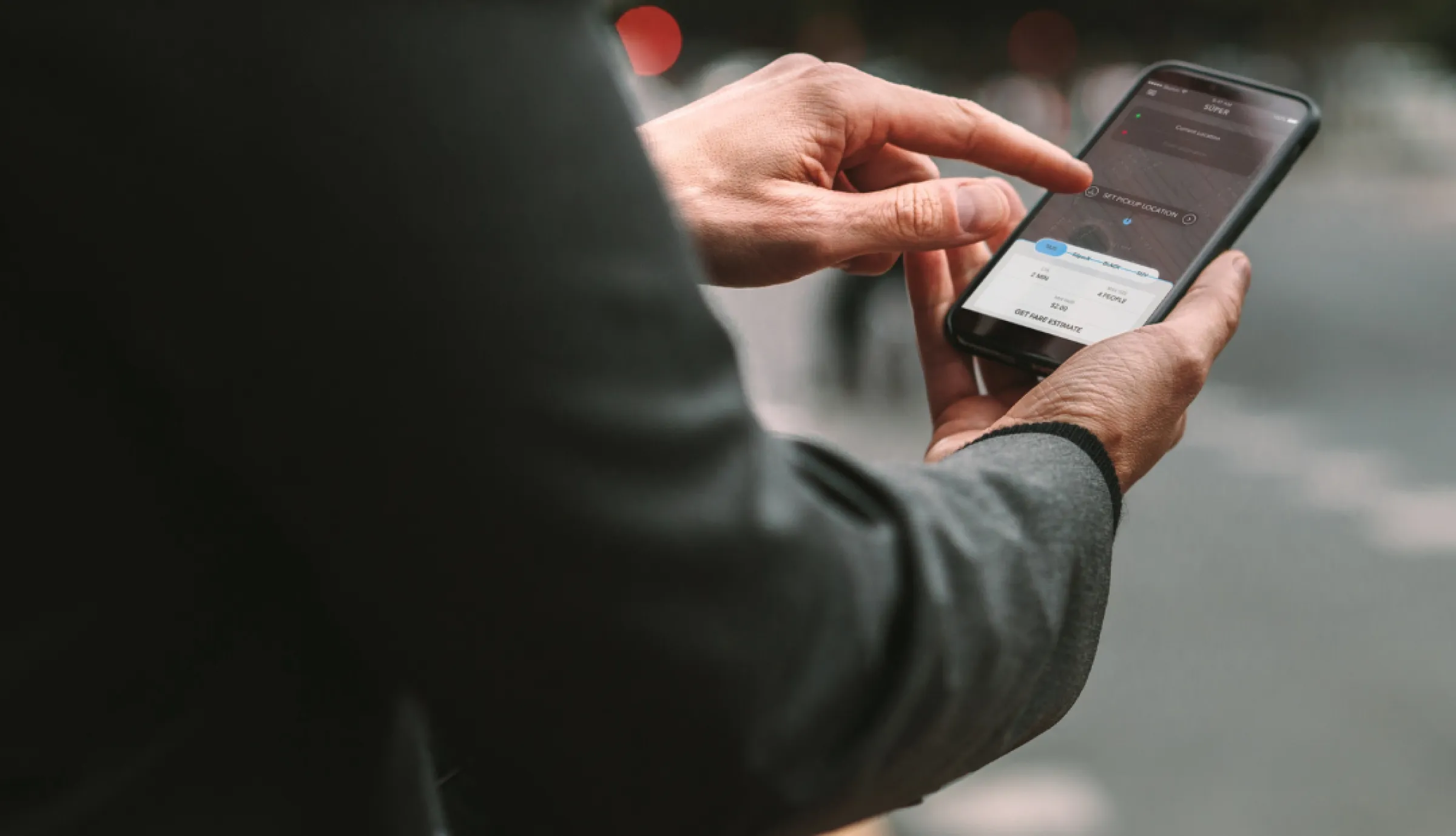 Person in dunkler Jacke hält ein Smartphone und tippt darauf.