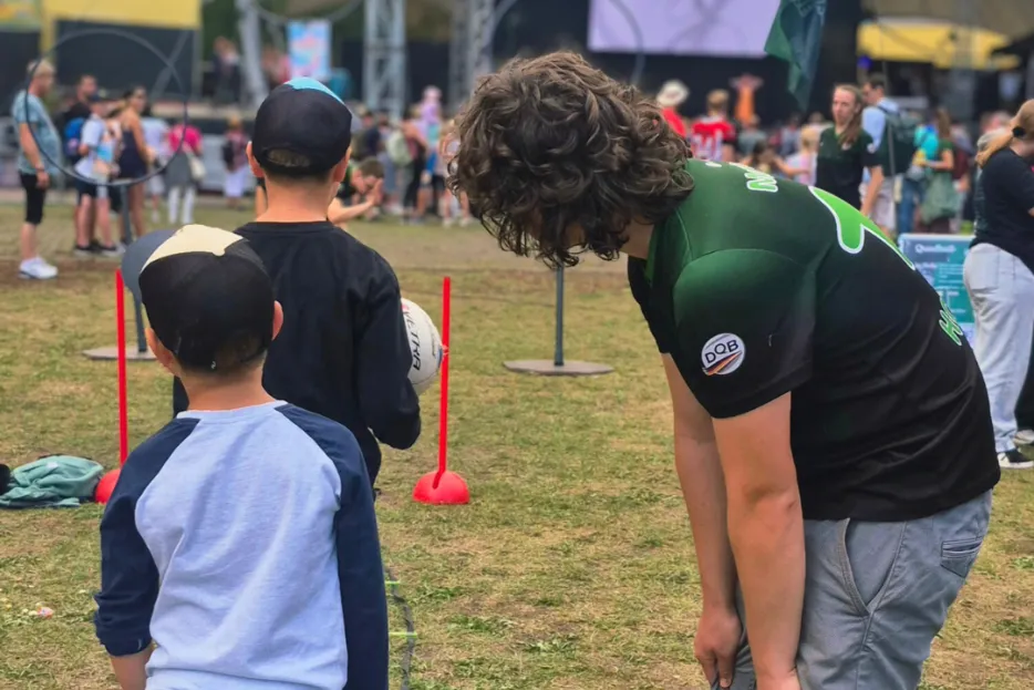 Ein Mann in grünem Trikot erklärt zwei jungen einen Quadball-Parcour