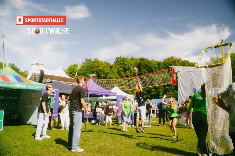 Menschen in Trikots spielen Volleyball auf Wiese