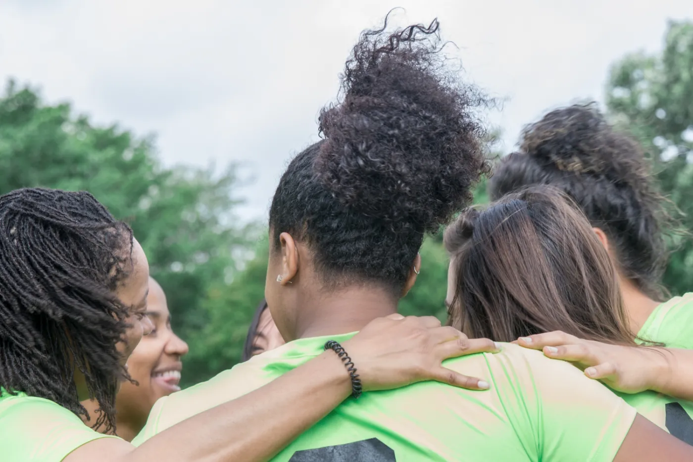 Frauen unterschiedlicher Hautfarben in Trikots bilden einen Teamkreis.