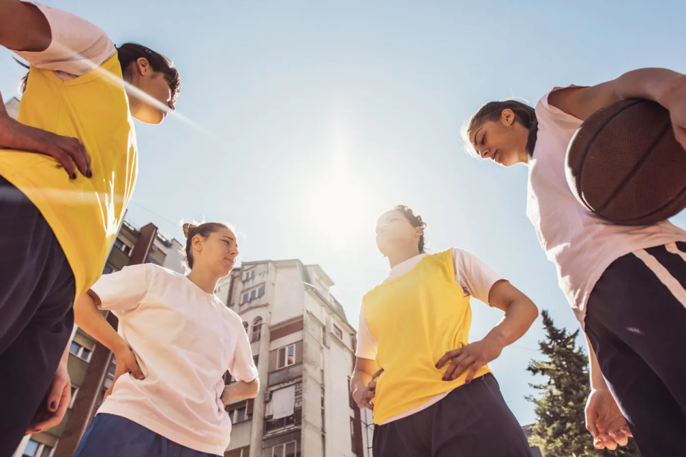 Streetball Vier Damen in Sportbekleidung stehen im Kreis, eine hält einen Basketball im Arm.