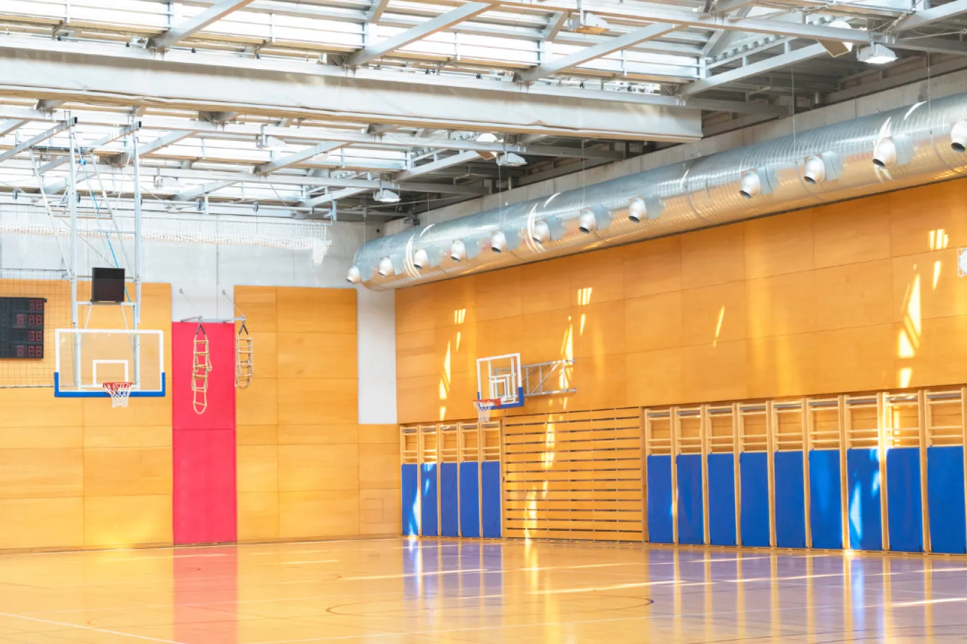 Symbolbild Turnhalle Zu sehen ist eine Turnhalle mit hellem Boden, Sprossenwänden, Basketballkörben...