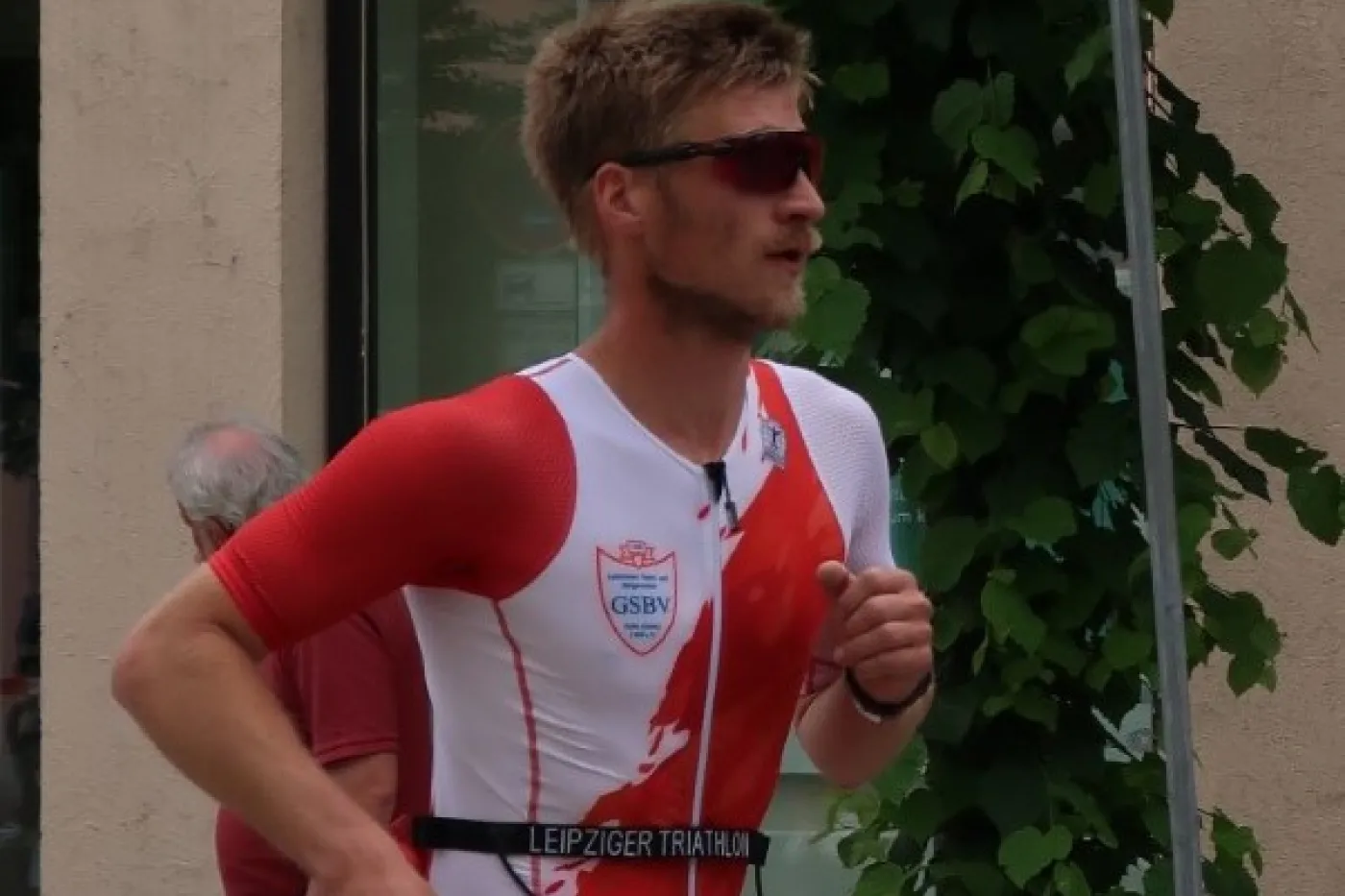 Max Zellmer rennt hinter einem Absperrband in rot-wei&szlig;em Laufanzug