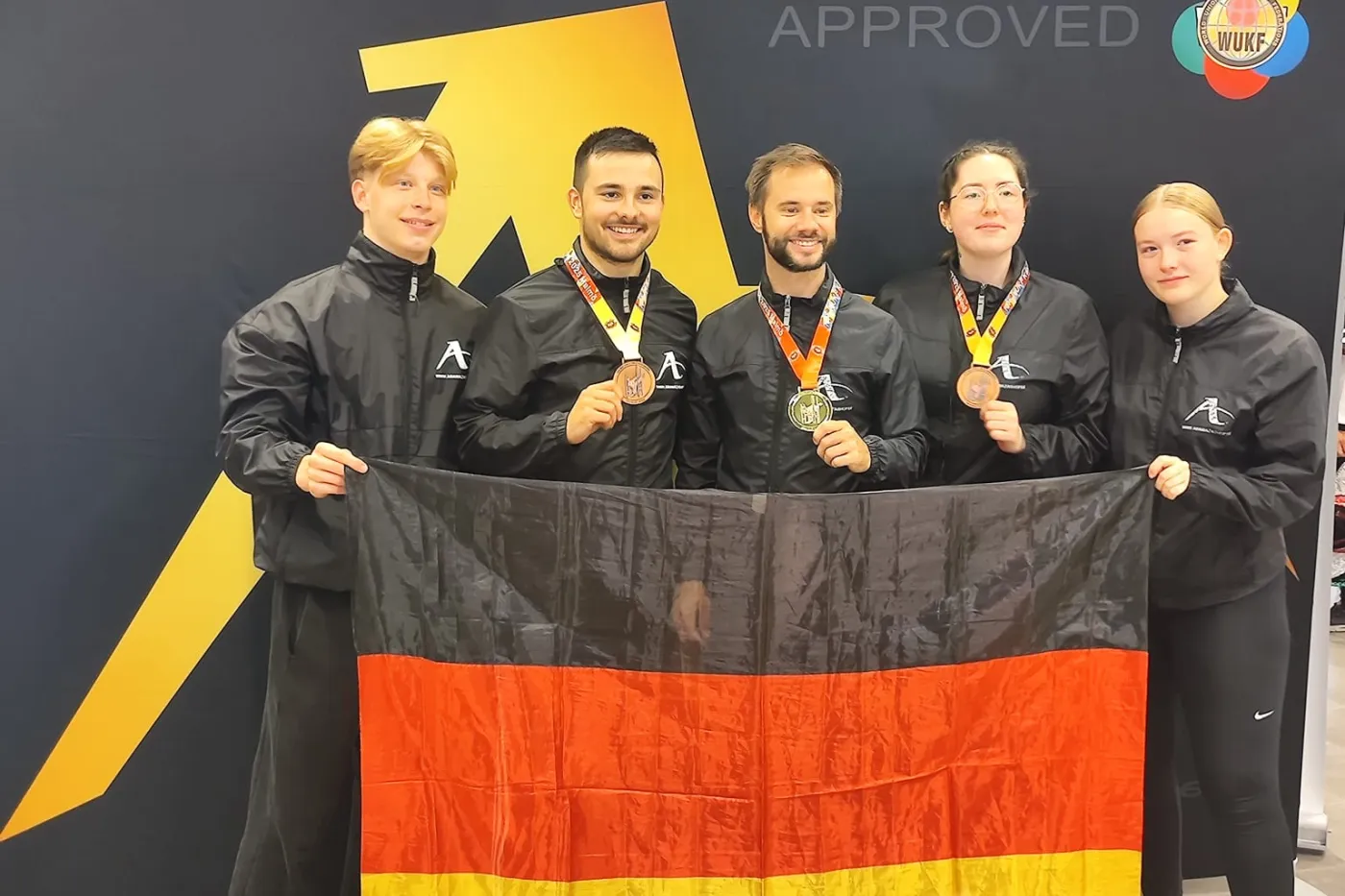 Die fünf Sportler des KIH posieren mit Deutschlandfahne.