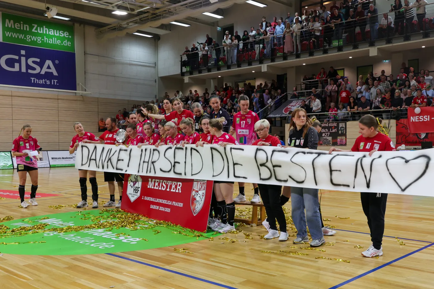 Die Wildcats halten ein Banner in ihrer Halle Richtung Fans mit Aufschrift: Danke, ihr seid die Besten!