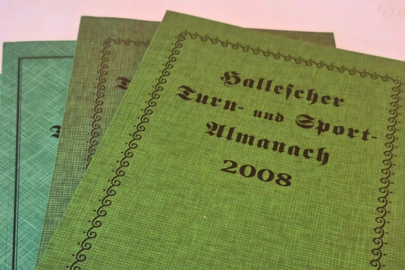 Mehrere Bücher in grünem Einband aufgefächert auf dem Tisch.