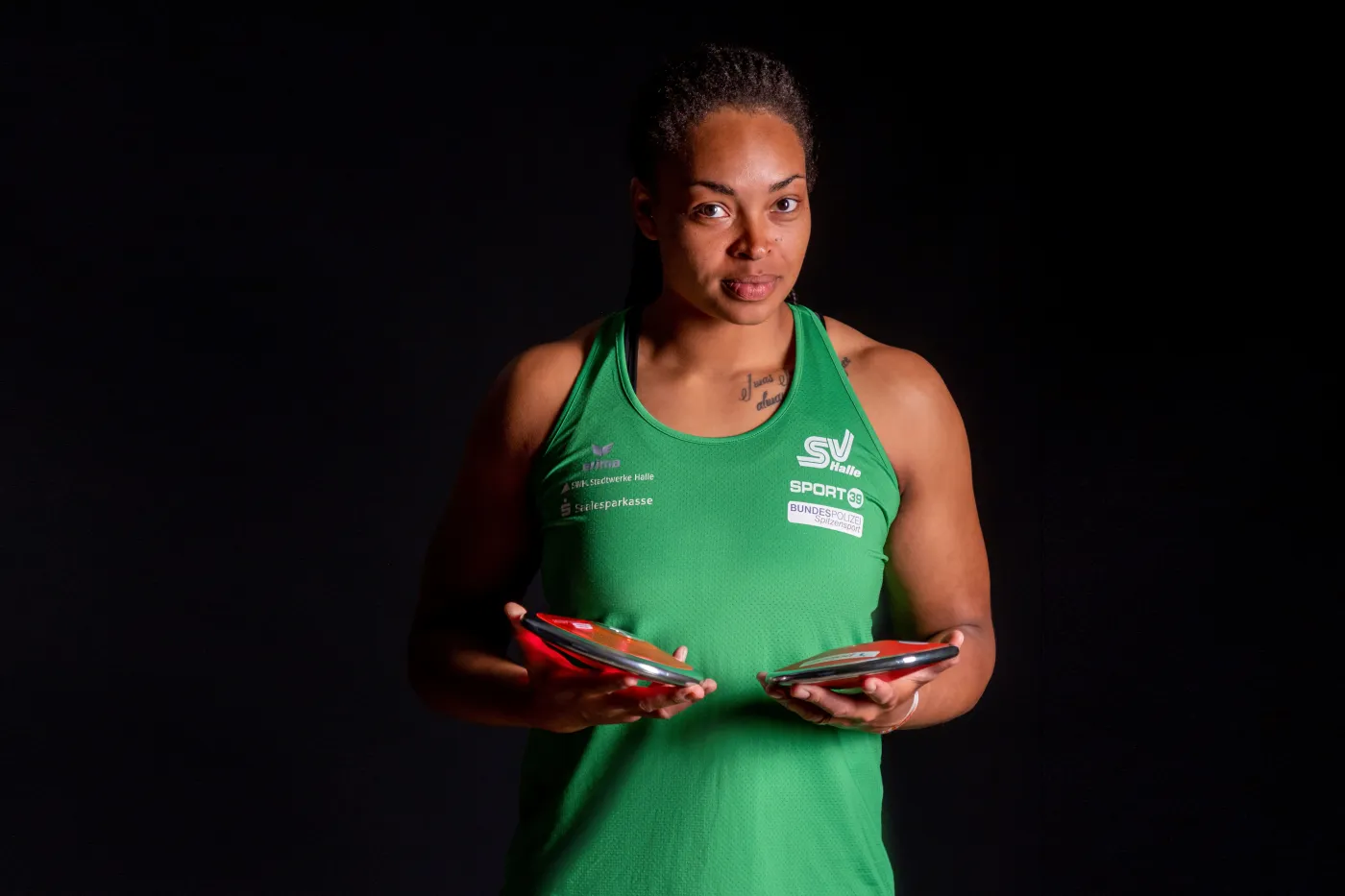 Diskusweferin Shanice Craft mit Diskus in der Hand vor dunklem Hintergrund.