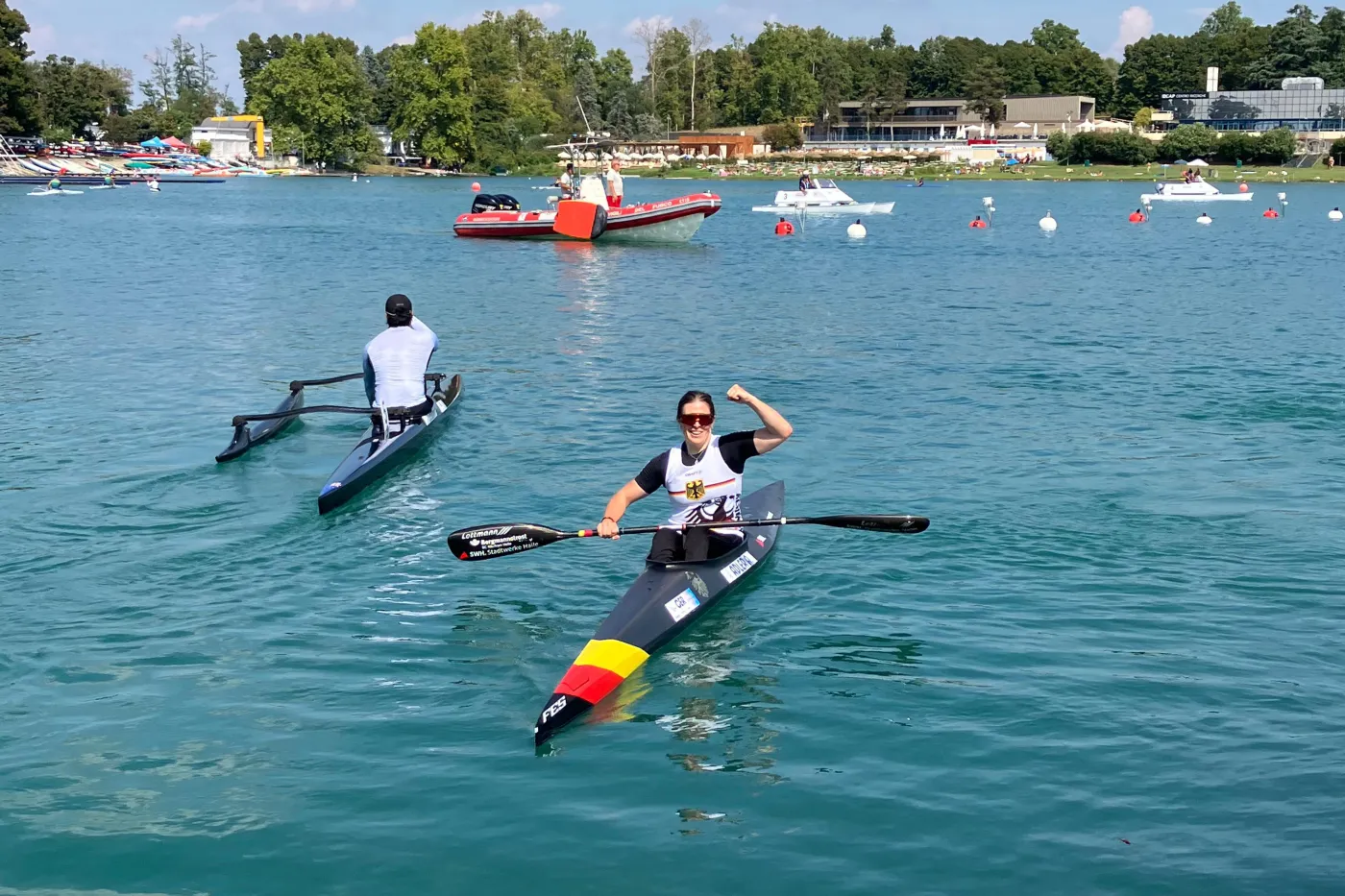 Anja Adler in ihrem Kanu im Wasser nach einem Rennen in Jubelpose.