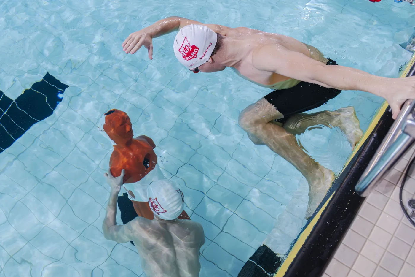 Zwei Schwimmer der DLRG im Wasser mit einer Rettungspuppe.