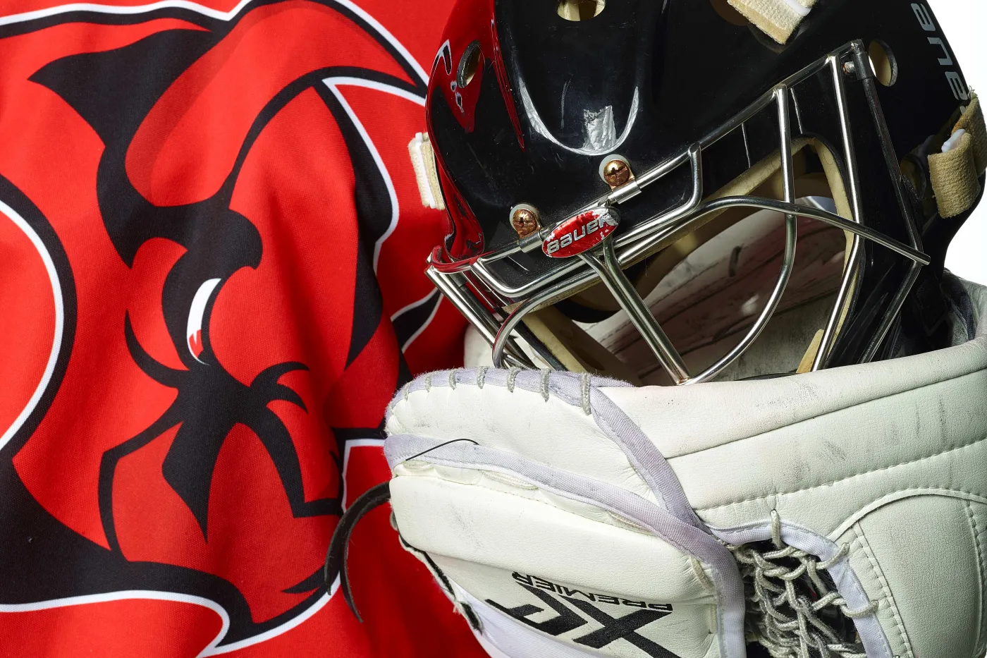 Saale Bulls Bildausschnitt: Oberkörper eines Eishockey-Torhüters, der im Handschuh seinen Helm hält.