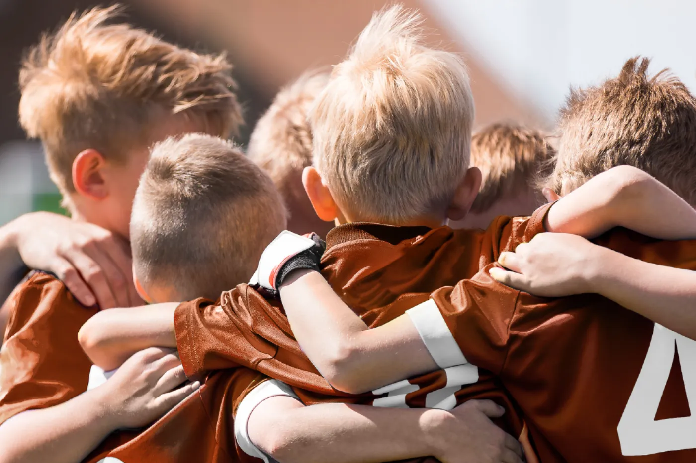 Zusammen ein Team Mehrere Jungen in Fußballtrikots bilden einen Teamkreis.