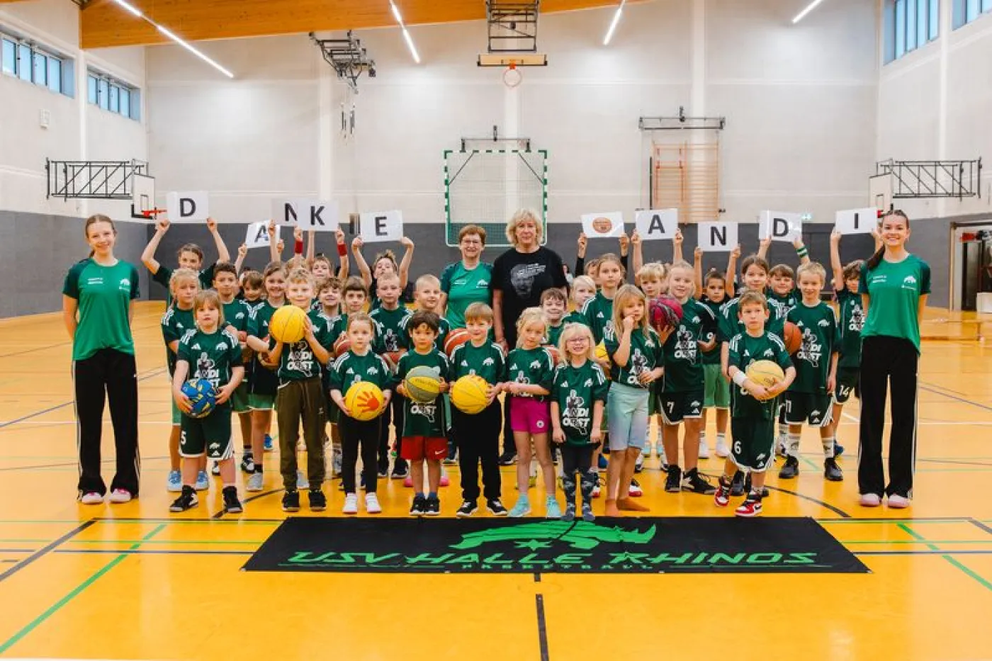 Mehrere Basketballkinder und Erwachsene posieren mit neuen Trikots und Basketbällen fürs Foto!