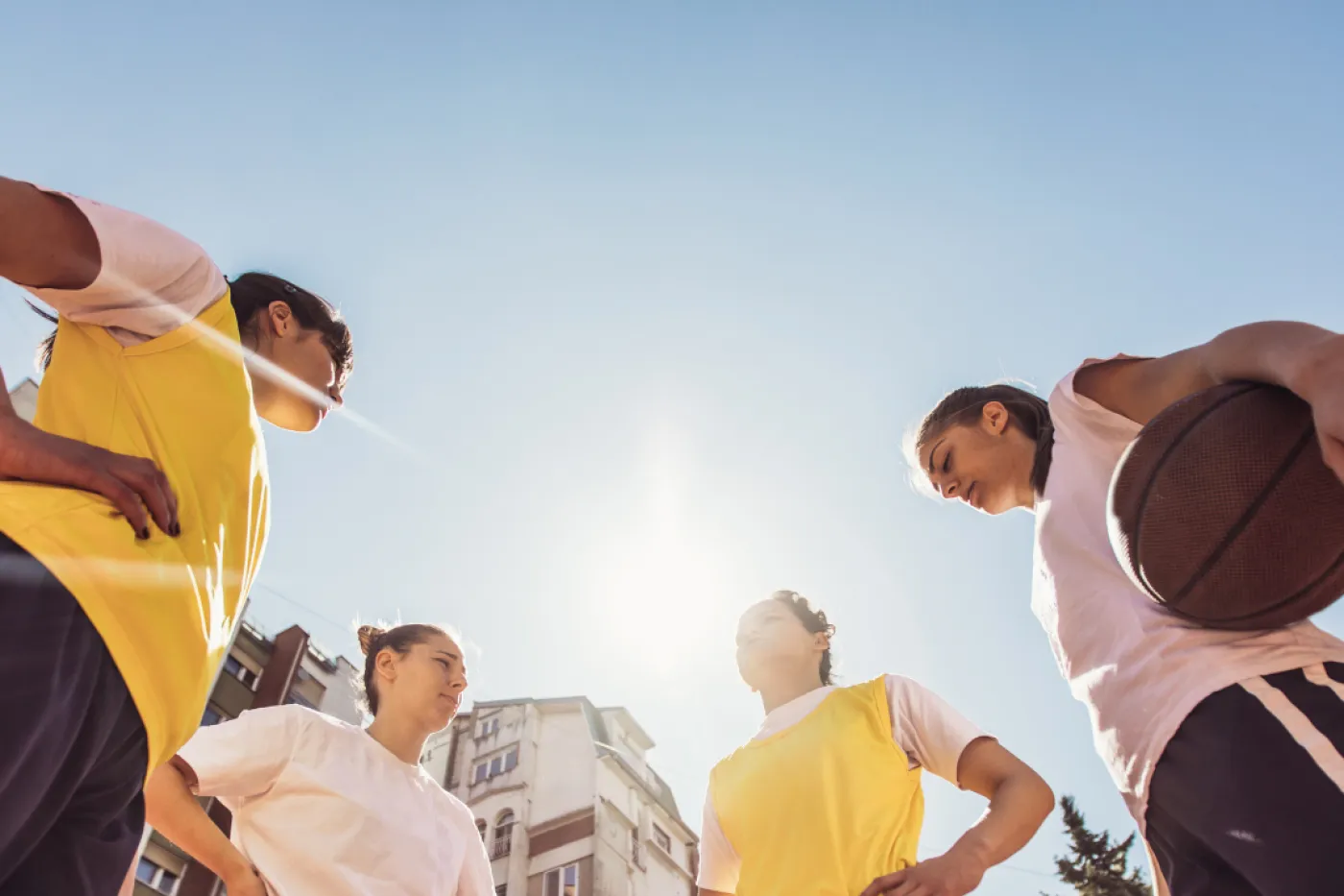 vier Basketballerinnen aus Froschperspektive vor blauem Himmel