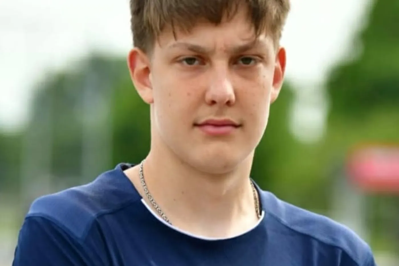 Junger Mann im blauen Trikot schaut mit verschr&auml;nkten Armen in die Kamera.