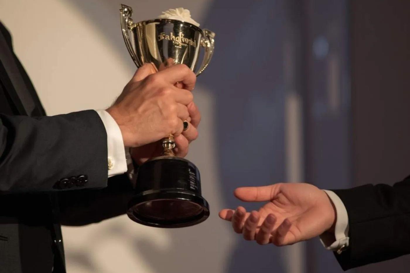 H&auml;nde eines Mannes &uuml;berreichen Pokal in andere H&auml;nde