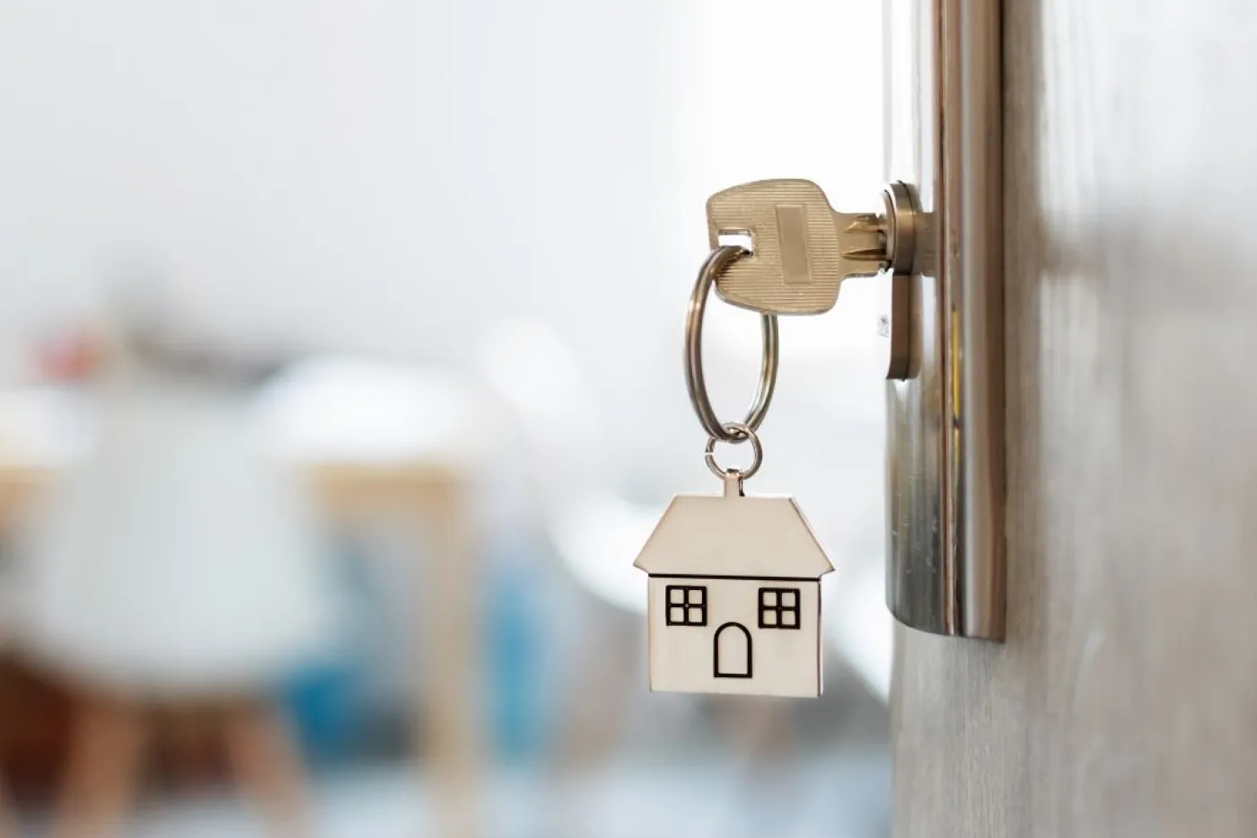 Schl&uuml;ssel mit Haus-Anh&auml;nger steckt in ge&ouml;ffneter T&uuml;r
