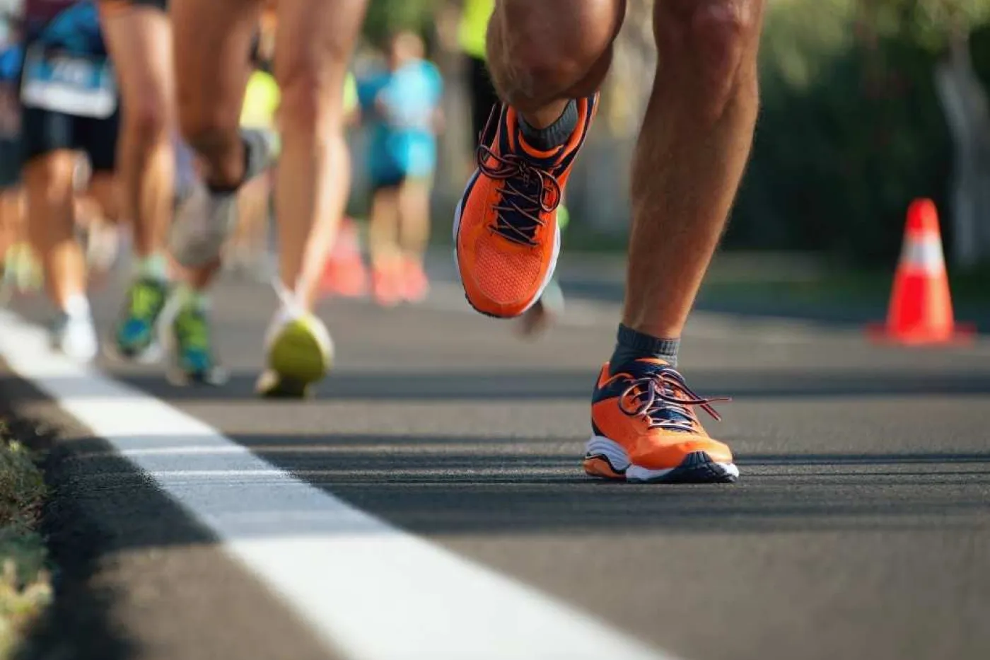 Man sieht Beine mehrerer Jogger in Laufschuhen auf einer Stra&szlig;e.