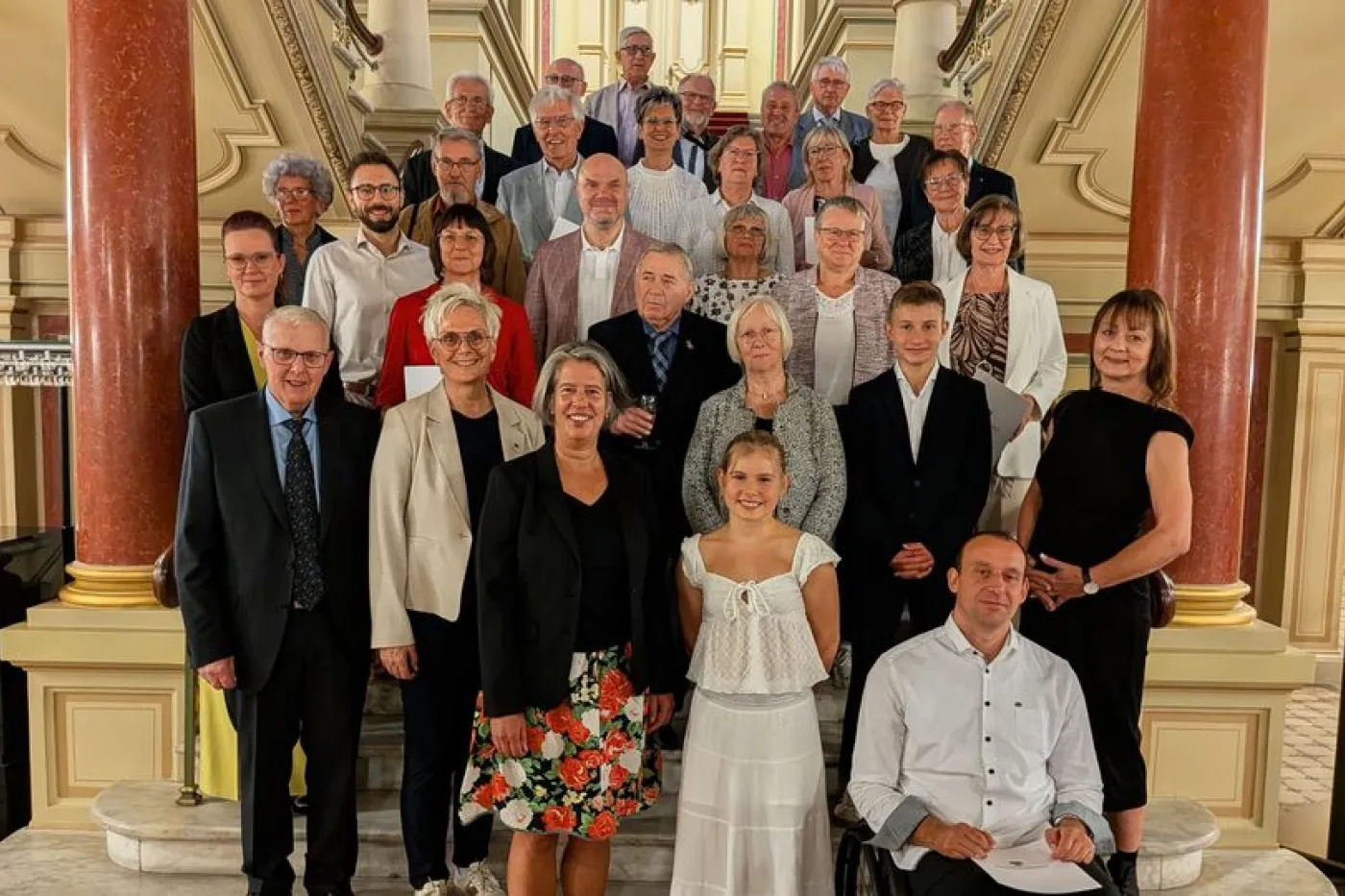 Elegant gekleidete Menschen posieren f&uuml;r Foto auf Treppe
