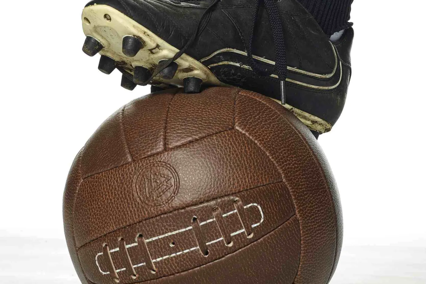 Fu&szlig;ballschuh auf altem braunen Lederfu&szlig;ball